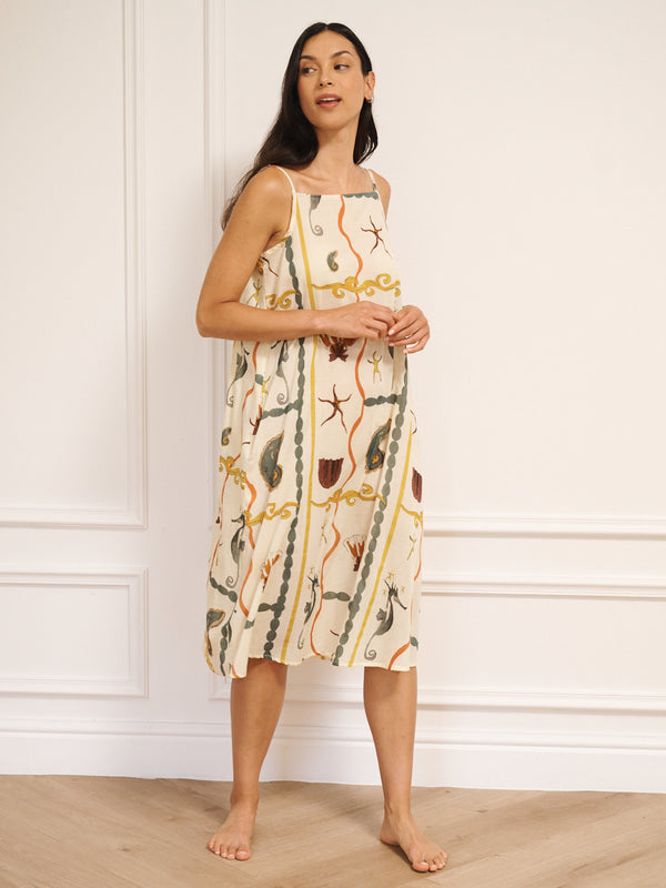 Model wearing women’s cotton voile midi nightdress with straight neckline and slim straps, featuring natural sea life tile print with seahorses, shells and starfish in a relaxed, flowing fit.