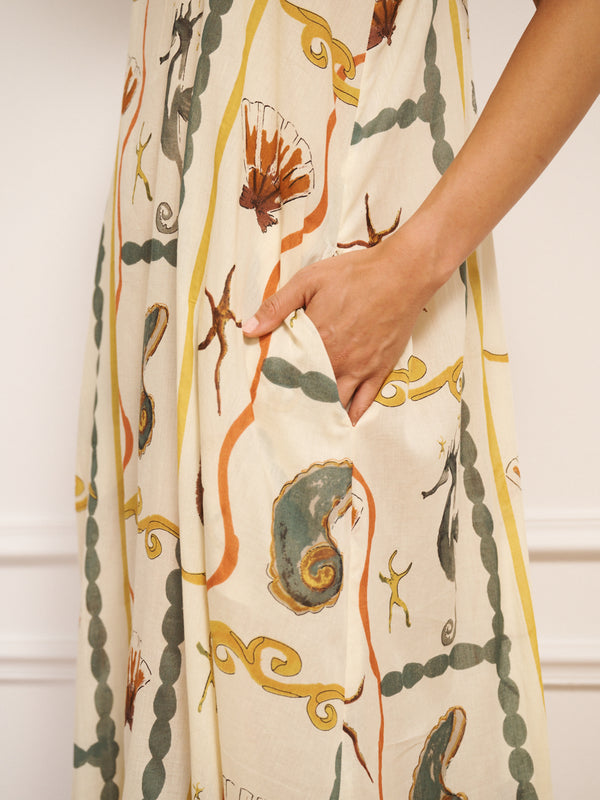 Model wearing women’s cotton voile midi nightdress with straight neckline and slim straps, featuring natural sea life tile print with seahorses, shells and starfish in a relaxed, flowing fit. Pocket detail
