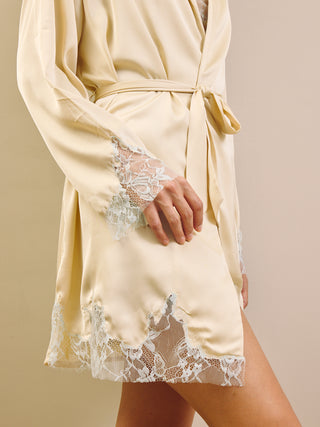 Cream-colored satin robe with lace trim on a beige background
