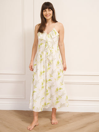 Woman wearing a floral nightie standing against a white wall.