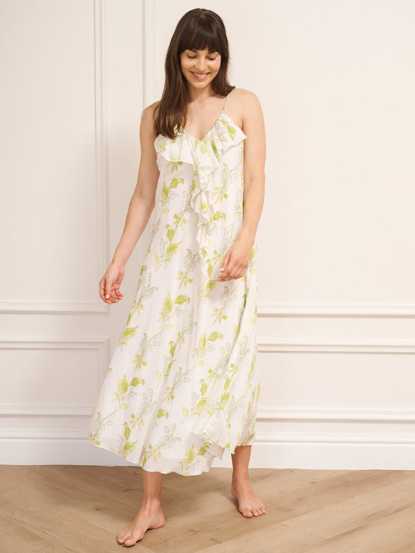 Woman wearing a floral night dress standing against a white wall.