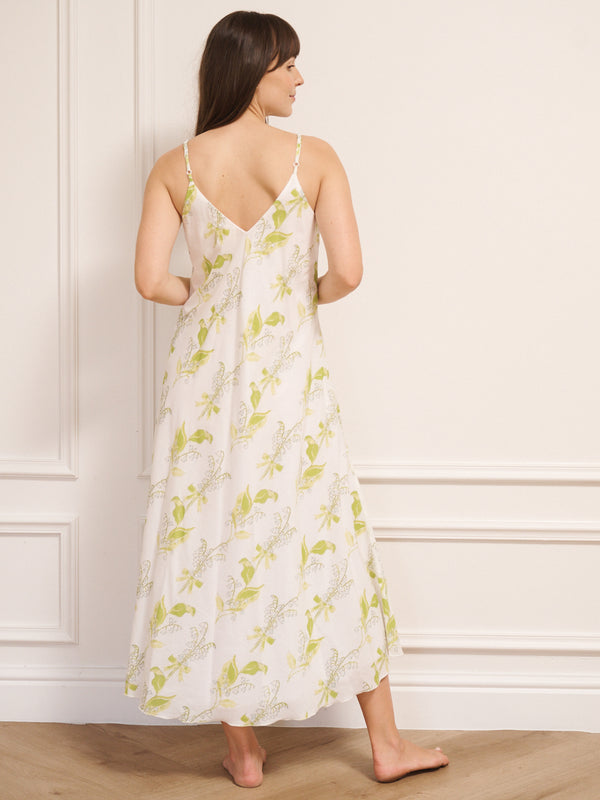 Woman wearing a white  night dress with  floral pattern against a white wall.