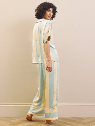 Woman wearing a striped pyhama standing against a plain wall.