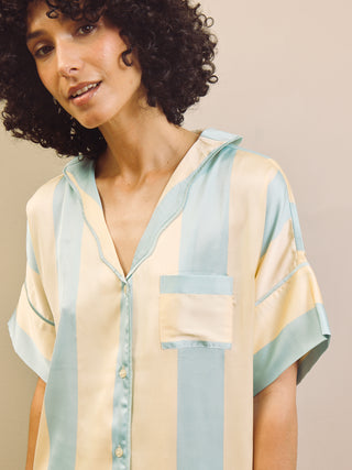 Woman wearing a blue and gold pyjama shirt on a beige background