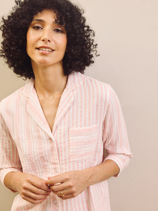 Woman wearing a pink striped pyjama shirt against a plain background