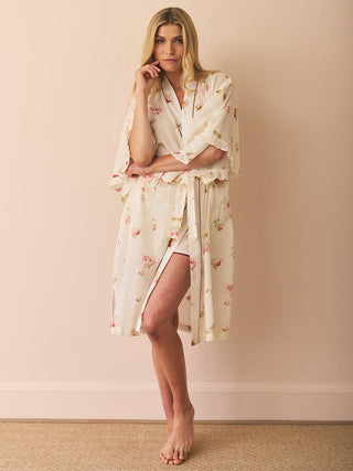 Woman wearing a floral dressing gown robe against a beige background