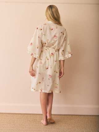 Woman wearing a floral dressing gown robe against a beige background, back detail