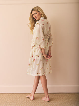 Woman wearing a floral dressing gown robe against a beige background