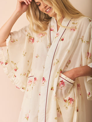 Woman wearing a floral dressing gown robe against a beige background
