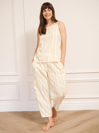Woman wearing a yellow and white striped pyjamas against a white wall.