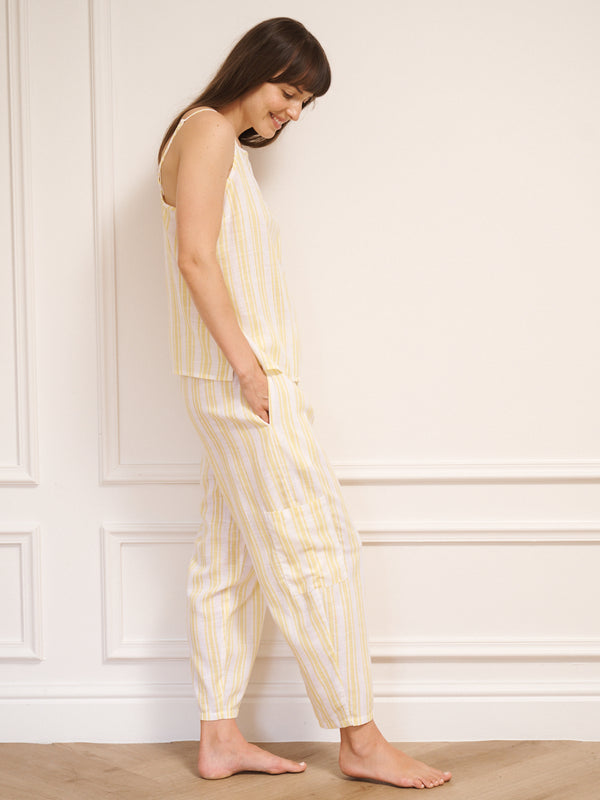 Woman wearing a yellow and white striped pyjamas against a white wall.