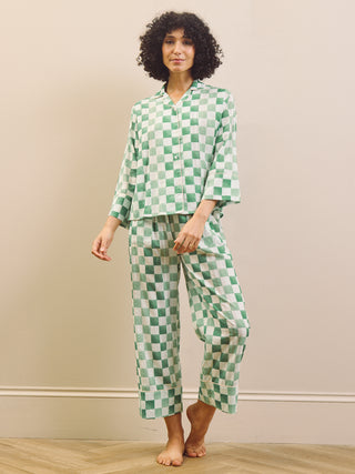 model wears green gingham check cropped pyjama set against a beige background