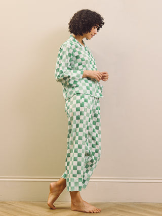 model wears green gingham check cropped pyjama set against a beige background