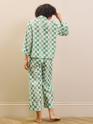 model wears green gingham check cropped pyjama set against a beige background