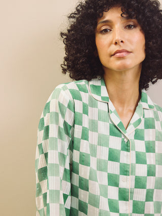 model wears green gingham check cropped pyjama set against a beige background