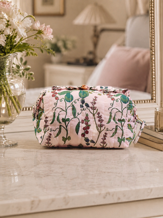 Floral-patterned cosmetic bag on a marble surface with a blurred background