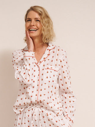 Woman wearing a  heart patterned pyjama set against a white wall.