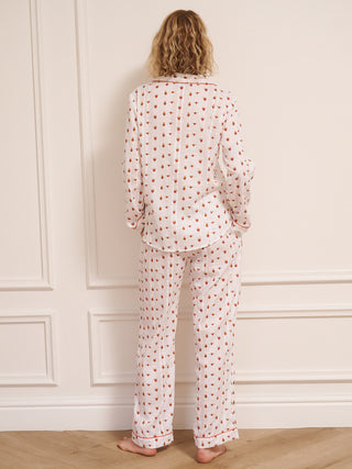 Woman wearing a  heart patterned pyjama set against a white wall. Back detail.