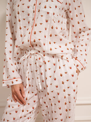 Woman wearing a  heart patterned pyjama set against a white wall.