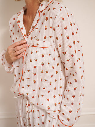 Woman wearing a  heart patterned pyjama set against a white wall.