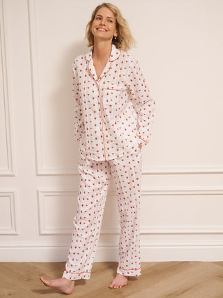 Woman wearing a heart patterned pyjama set against a white wall.