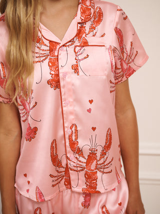 Pink satin pyjama top with red lobster and heart patterns worn by a tween