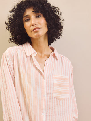 Woman wearing a pink striped pyjama shirt against a neutral background
