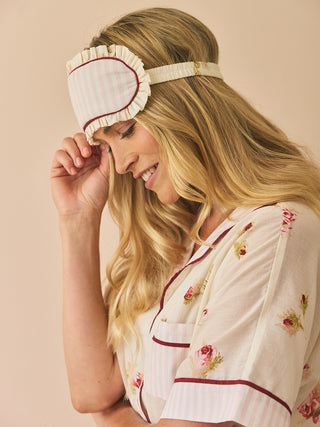 Woman wearing floral pyjamas and sleep mask on a beige background