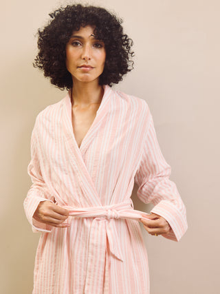 Woman wearing a pink striped robe against a plain background