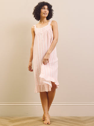 Woman wearing a pink nightgown against a plain background