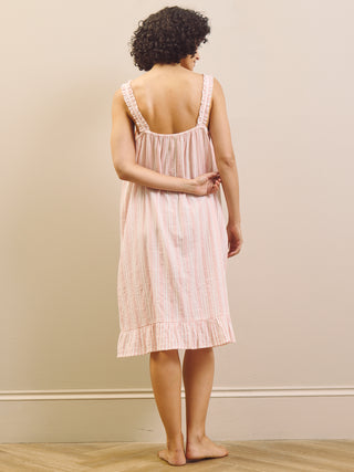 Woman wearing a pink striped nightgown against a plain background