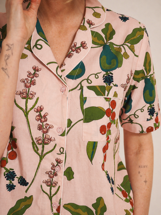 Person wearing a pink floral patterned pyjama shirt with green leaves and red berries.