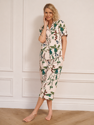 Woman wearing a floral pyjama set against a white wall.