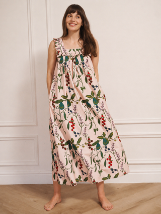 Woman wearing a floral night dress standing against a white wall.