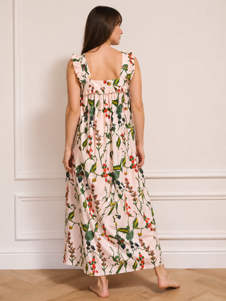 Woman wearing a floral night dress standing against a white wall.
