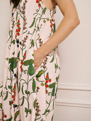 Close-up of a floral nightdress with green leaves, pears and red berries. Models has her hand in a pocket. on a plain background