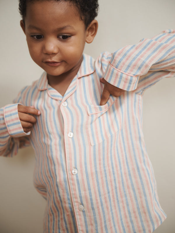 Child wearing a striped shirt with rolled-up sleeves against a neutral background