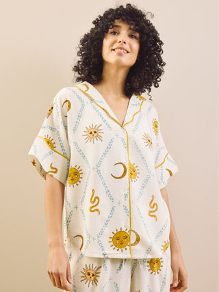 Woman wearing a cream pyjama set with sun and moon patterns in a minimal indoor setting