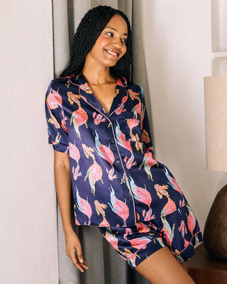 Woman in a floral pajama set standing in a bedroom.