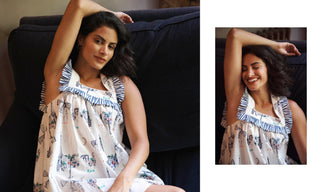 A woman wearing a sleeveless white nightgown with blue and white Parisian patterns and ruffled trim, posed on a dark couch. A smaller inset photo on the right shows a smiling view of the same outfit.