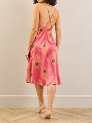 Back image of a pink satin night dress with peacock feather print on a model. 
