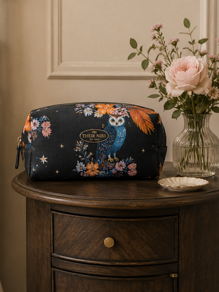 Floral-patterned makeup bag on a wooden nightstand with a vase of flowers.