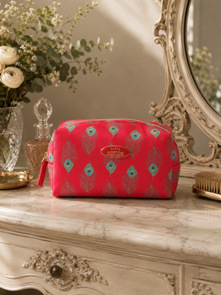 Red cosmetic bag with peacock pattern on a decorative table