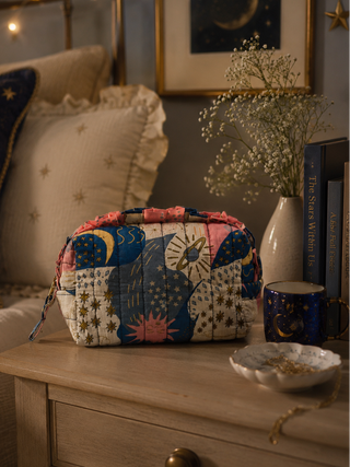 Colorful patchwork bag on a wooden nightstand with decorative pillows and books in the background