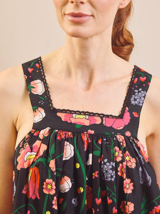 Close-up of a woman wearing a black floral nightdress with pink, orange, and green flowers, featuring a square neckline with lace trim.