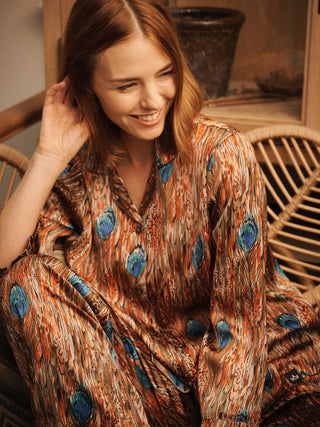 Model wears festival feather print pyjama set while sat on a chair