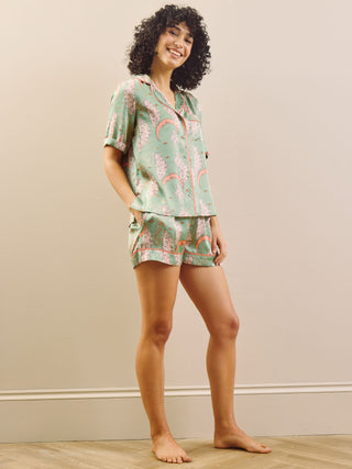 Model wearing a green moon and clouds design short pyjama set against a beige background