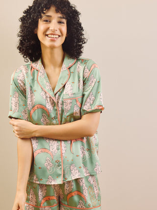 Model wearing a green moon and clouds design short pyjama set against a beige background