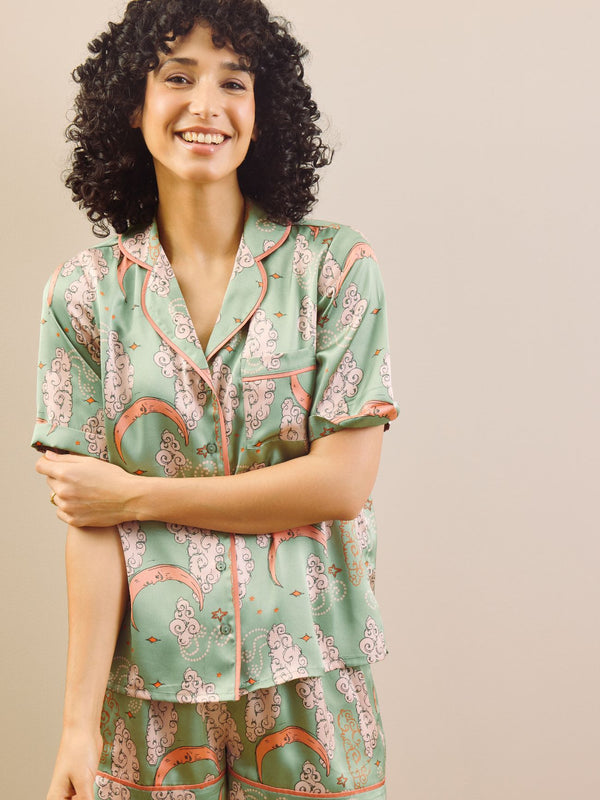 Model wearing a green moon and clouds design short pyjama set against a beige background