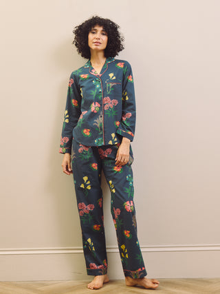 Woman wearing a navy blue floral pyjama set against a plain background
